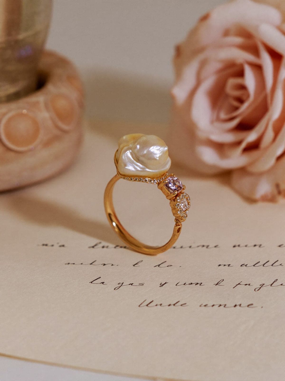 Champagne gold ring crowned with a baroque pearl standing on aged parchment with ink handwriting